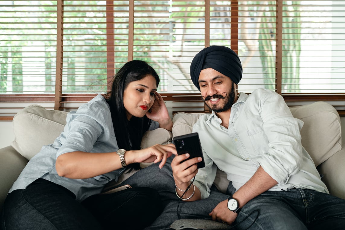 Happy Indian couple using smartphone together